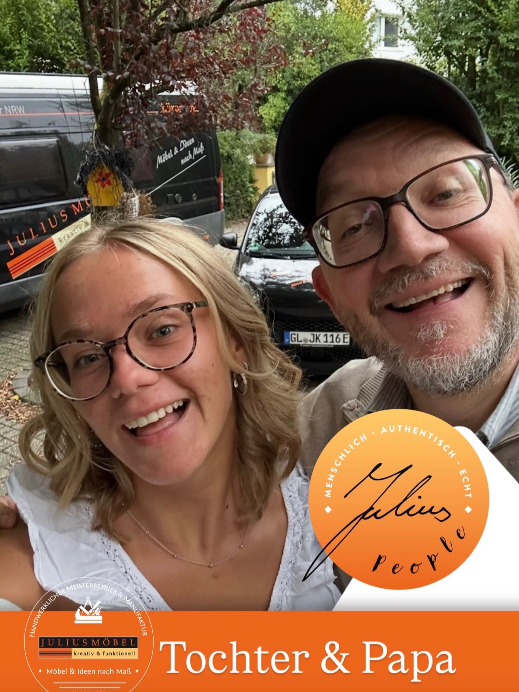 Eine lächelnde Frau und ein Mann machen draußen in der Nähe eines Kleinbusses ein Selfie. Auf einem orangefarbenen Anstecker steht „Julius People“. Der Text unten lautet „Tochter & Papa“. Im Hintergrund sind Bäume und Autos zu sehen.