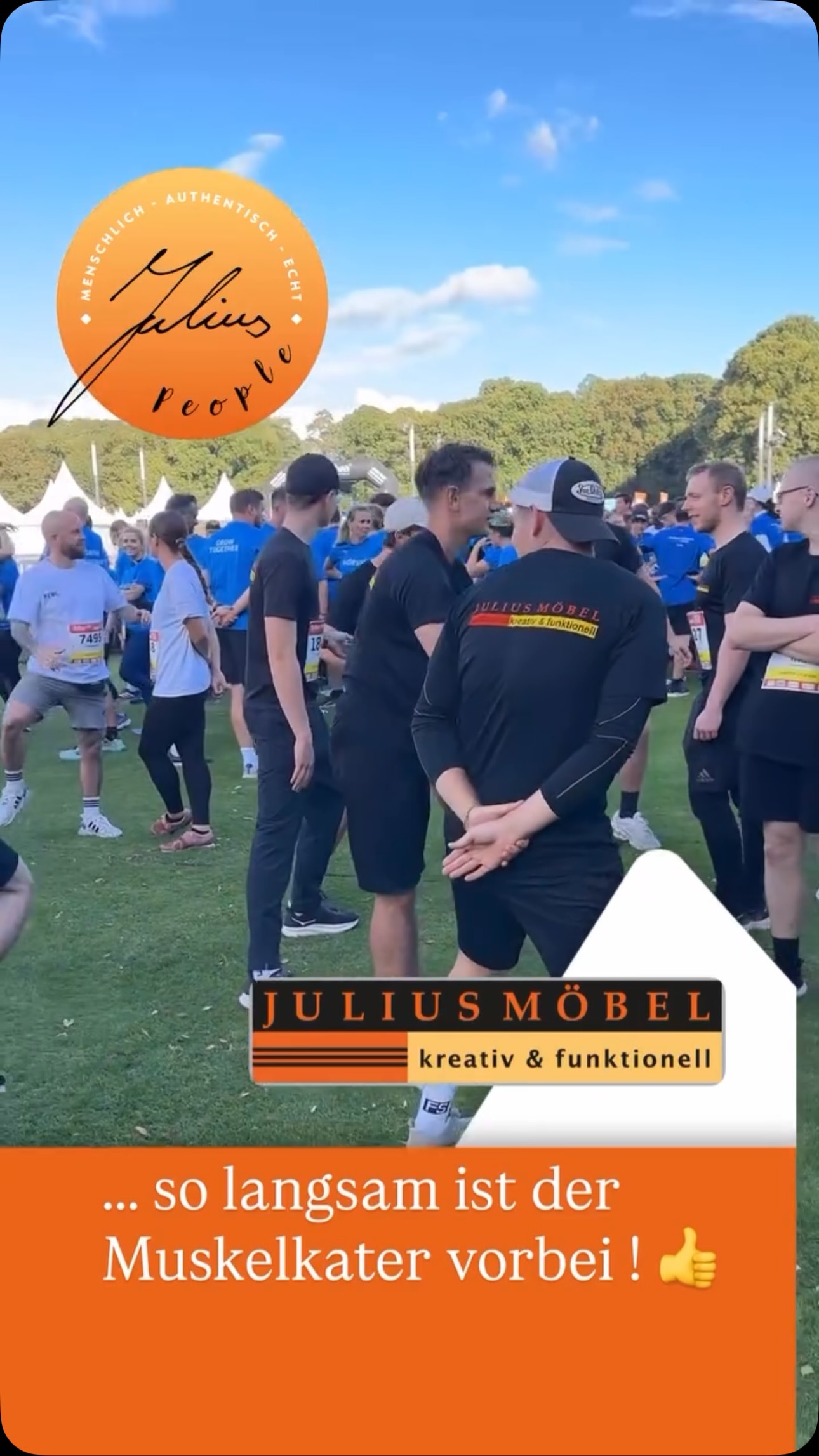 Eine Gruppe von Menschen in Sportkleidung steht bei einer Veranstaltung im Freien und macht Dehnübungen. Ein orangefarbenes Banner mit der Aufschrift „JULIUSMÖBEL“ und einem deutschen Text überlagert das Bild. Im Hintergrund sind Bäume und Zelte zu sehen.