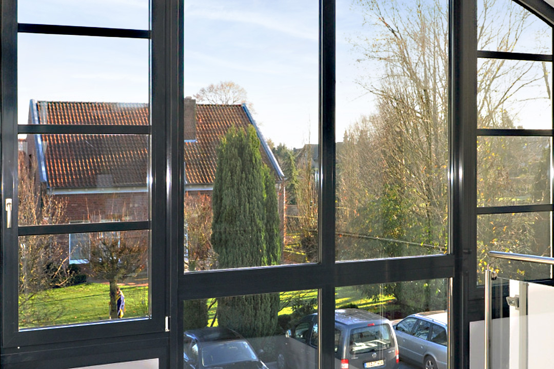 Aluminiumfenster nach Maß: anthrazitfarbene, raumhohe Fensterfront mit schmalen Rahmen und Blick ins Grüne