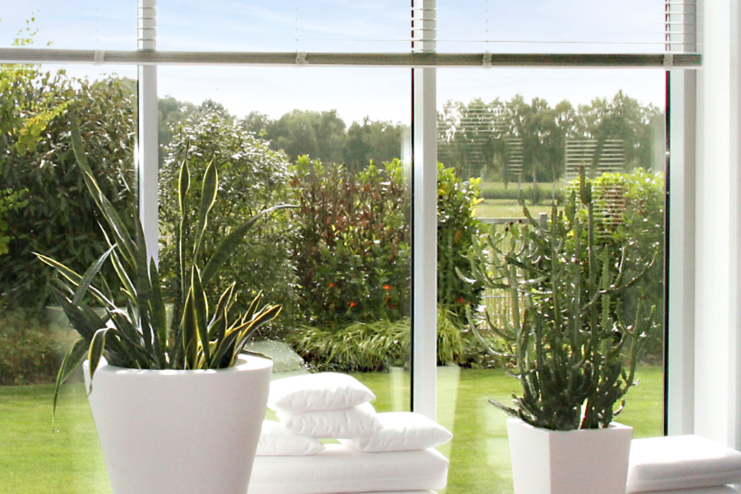 Holz-Alu-Fenster nach Maß: raumhohe Fensterfront mit schlanken Rahmen und Blick in einen sonnigen Garten