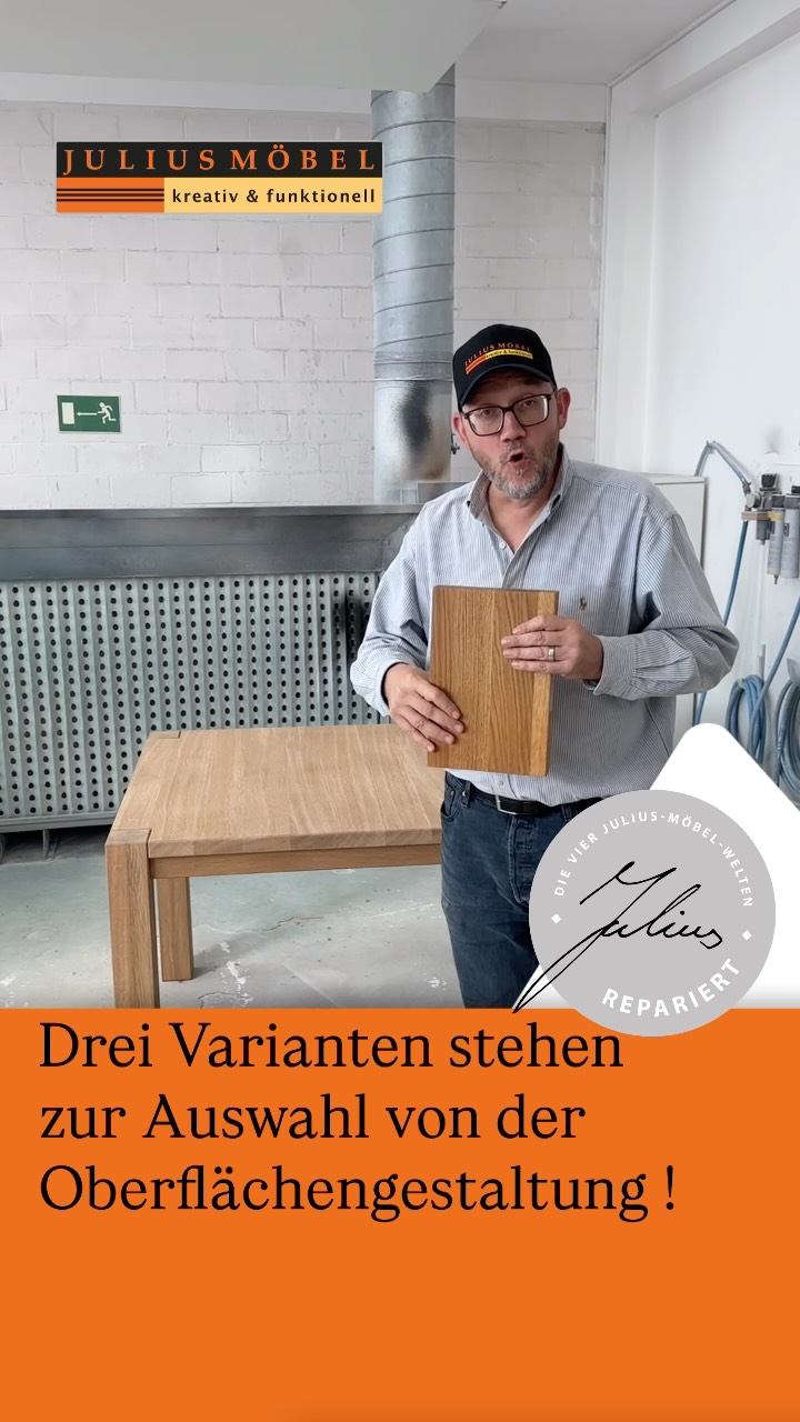Ein Mann steht in einer Werkstatt neben einem Holztisch und hält drei Muster für Holzoberflächenbehandlungen in der Hand. Der Text stellt drei Optionen für die Oberflächenbehandlung vor. Das Logo lautet „Julius Möbel“. Im Hintergrund sind Industrierohre und Werkzeuge zu sehen.