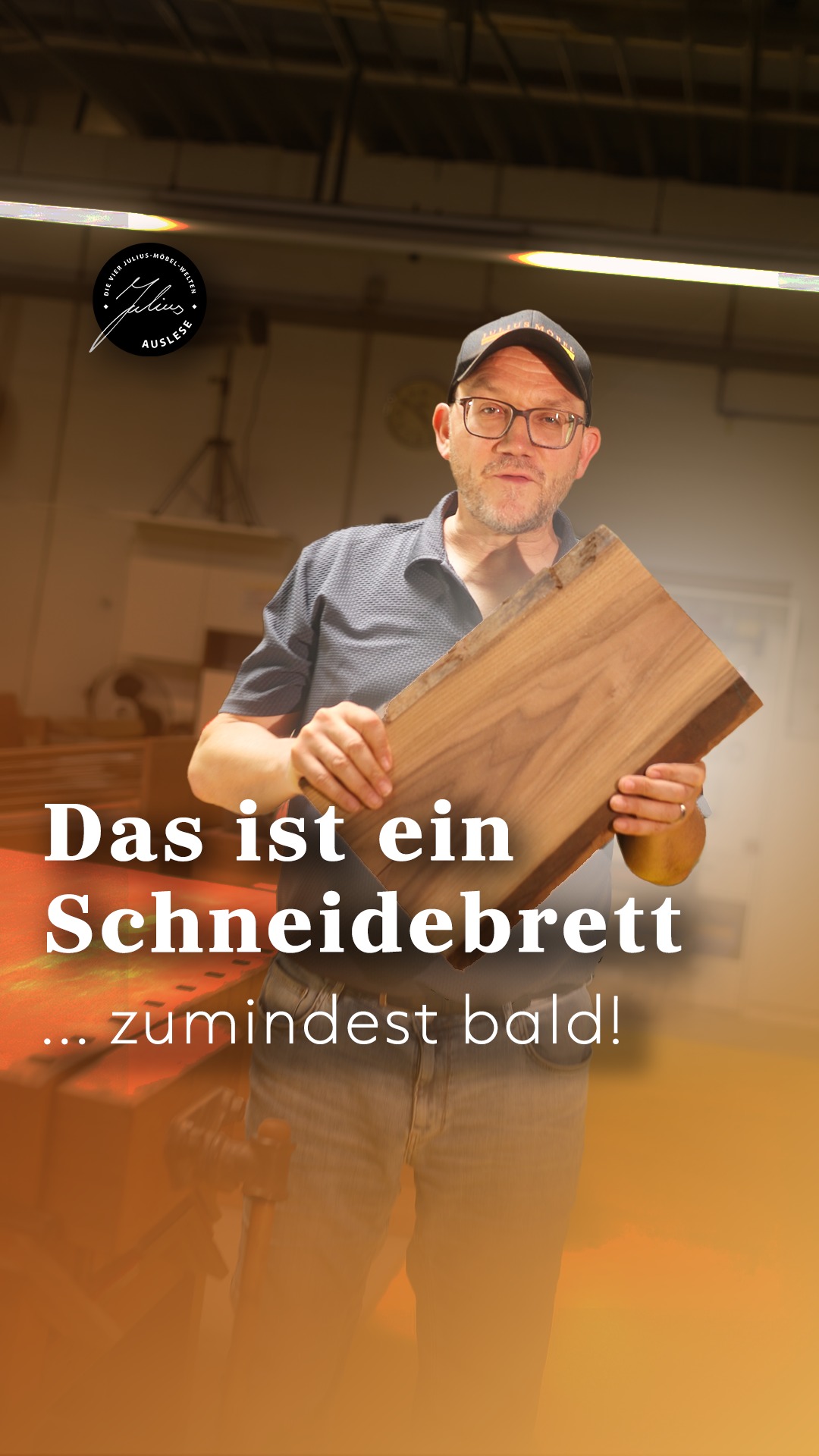 Ein Mann mit Brille und Mütze hält in einer Werkstatt ein Holzbrett hoch. Der deutsche Text lautet: „Das ist ein Schneidebrett … zumindest bald!“, was so viel bedeutet wie: „Das ist ein Schneidebrett … zumindest bald!“.