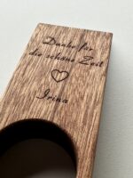 Ein „Weinflaschenhalter Balance“ aus Holz, graviert mit dem deutschen Text „Danke für die schöne Zeit ♥ Irina“, auf einer hellen Oberfläche platziert.